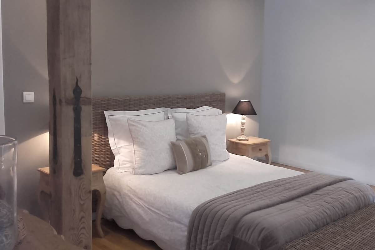 Ein Schlafzimmer mit einem Bett, Kissen, einer Nachttischlampe und einem Nachttisch.