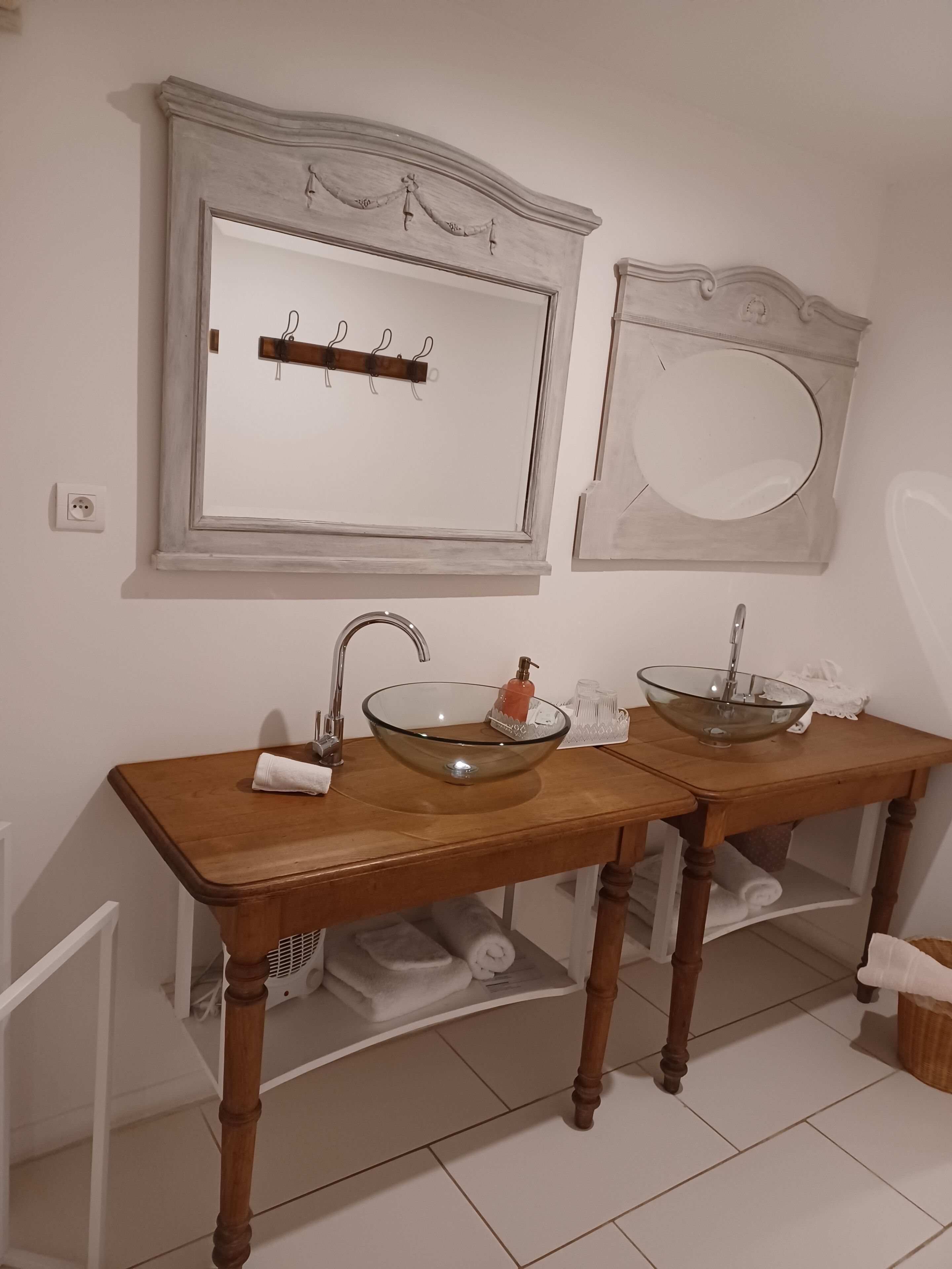 A bathroom with two glass bowl sinks, wooden vanity, and a mirror with a decorative frame.