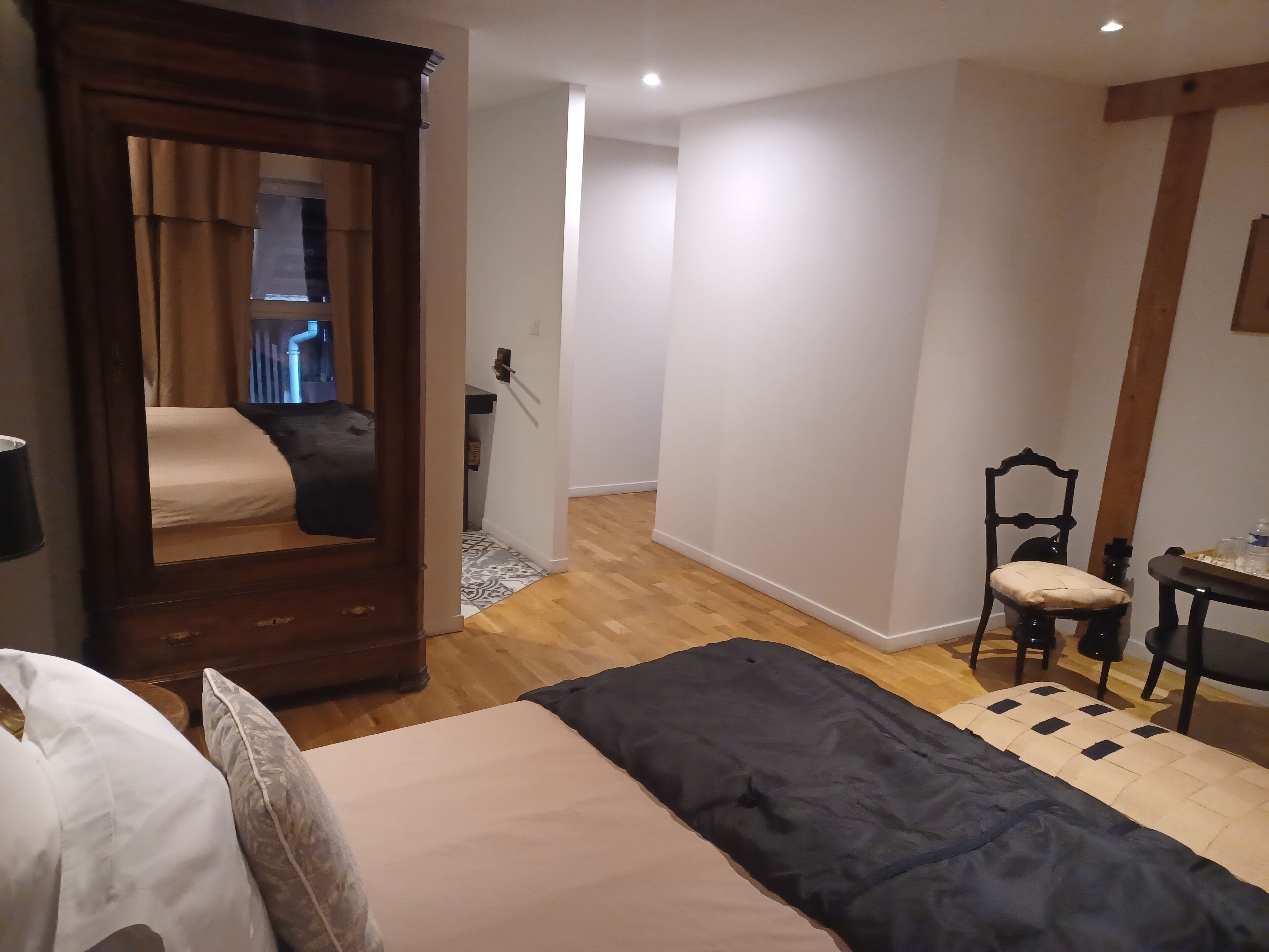 A bedroom with a bed, a chair, a table, and a mirror.