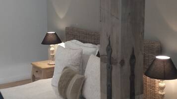 A bedroom with a large bed, two bedside tables with lamps, a wooden post, and a curved ceiling.