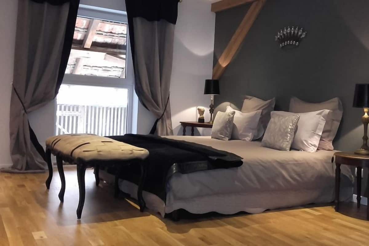Ein Schlafzimmer mit einem Bett, zwei Nachttischen, einer Bank und Blick ins Freie.