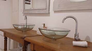 Un baño con dos lavamanos de cristal, tocador de madera y espejos.