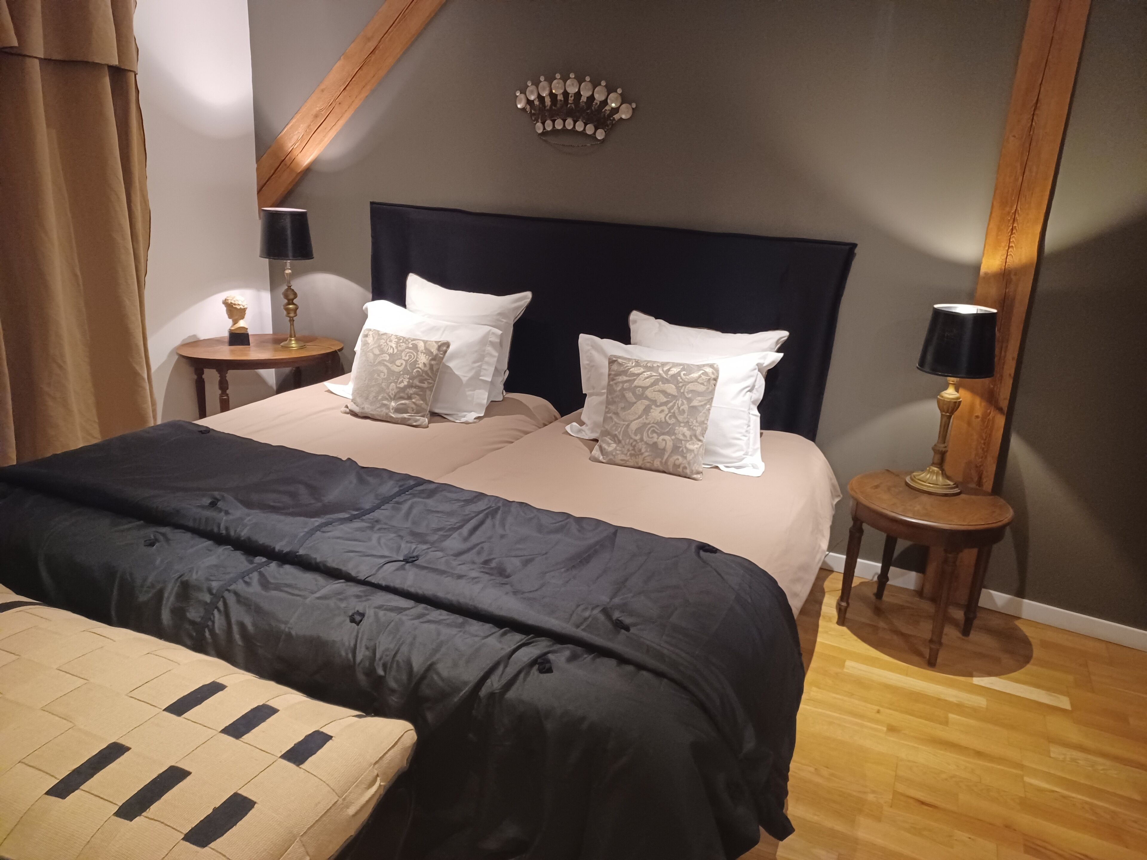 Un dormitorio ordenado con una cama grande, dos mesitas de noche y una corona decorativa en la pared.