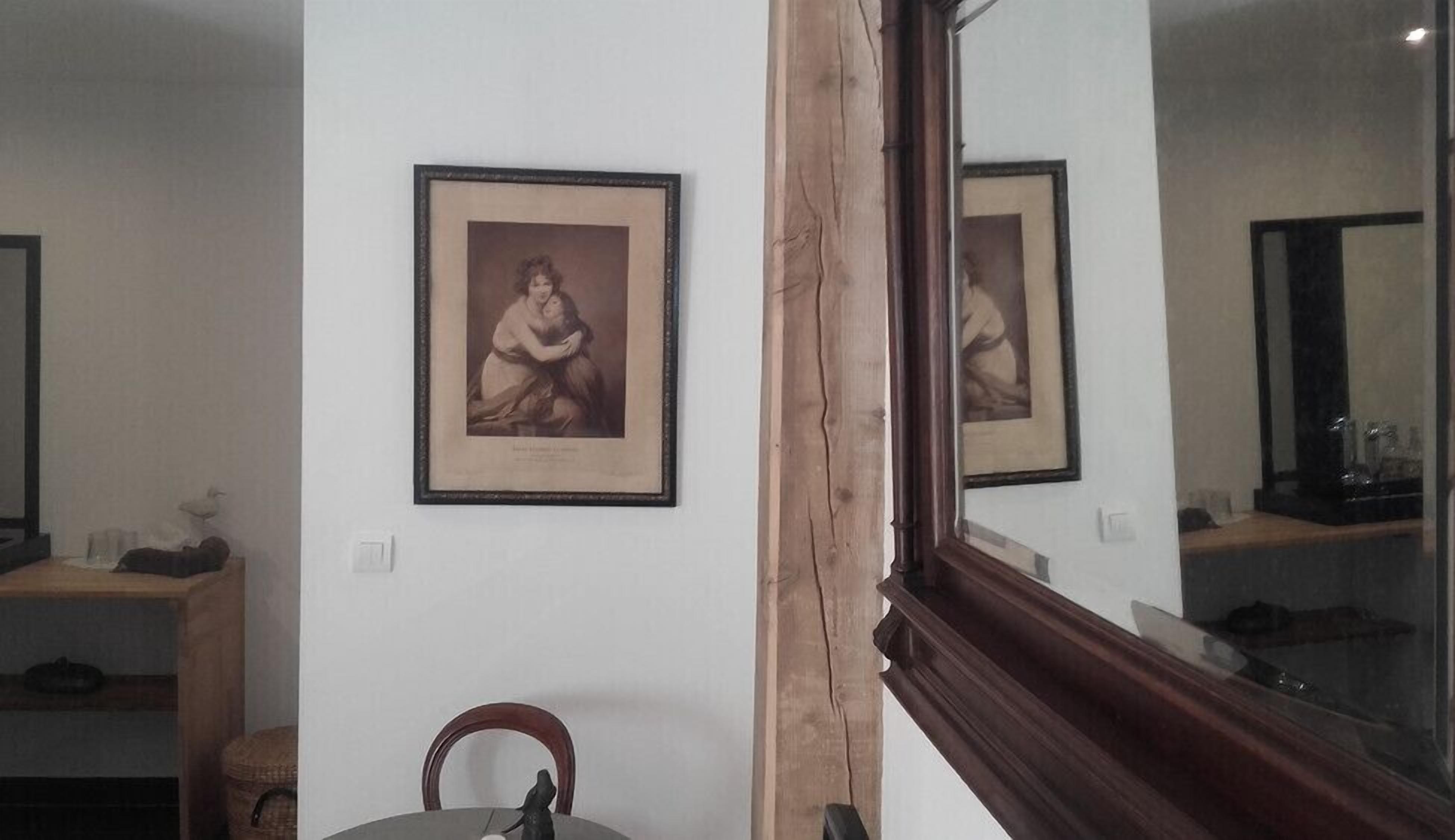 Une pièce comprenant une chaise en bois, une petite table et deux tableaux encadrés accrochés au mur.
