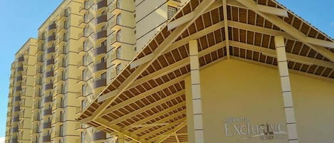 Un hotel de varios pisos con una entrada destacada y un área techada.