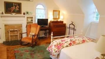 Un dormitorio con cama, una silla, un escritorio, un aparador y una chimenea.