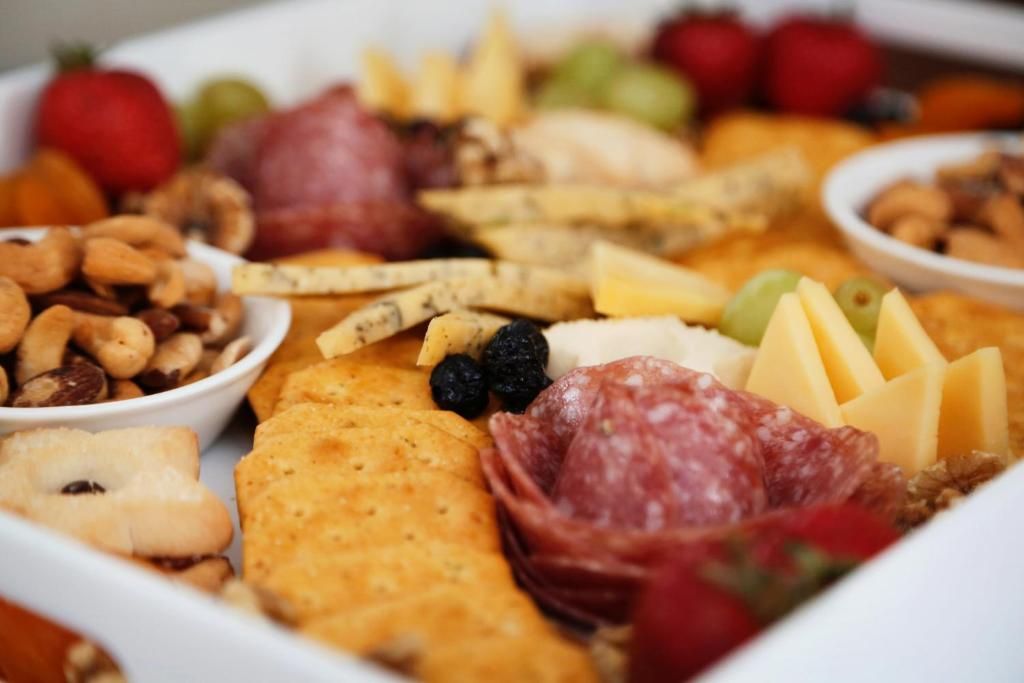 A charcuterie board with various cheeses, meats, fruits, and nuts.