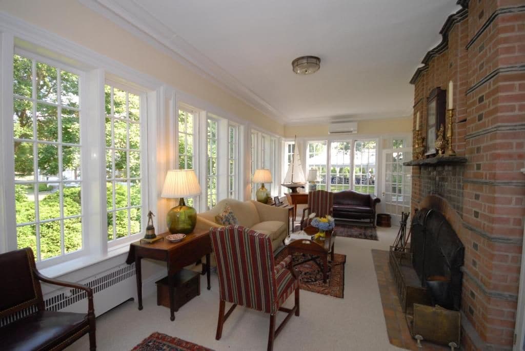 A spacious living room with large windows, a fireplace, and classic furniture.