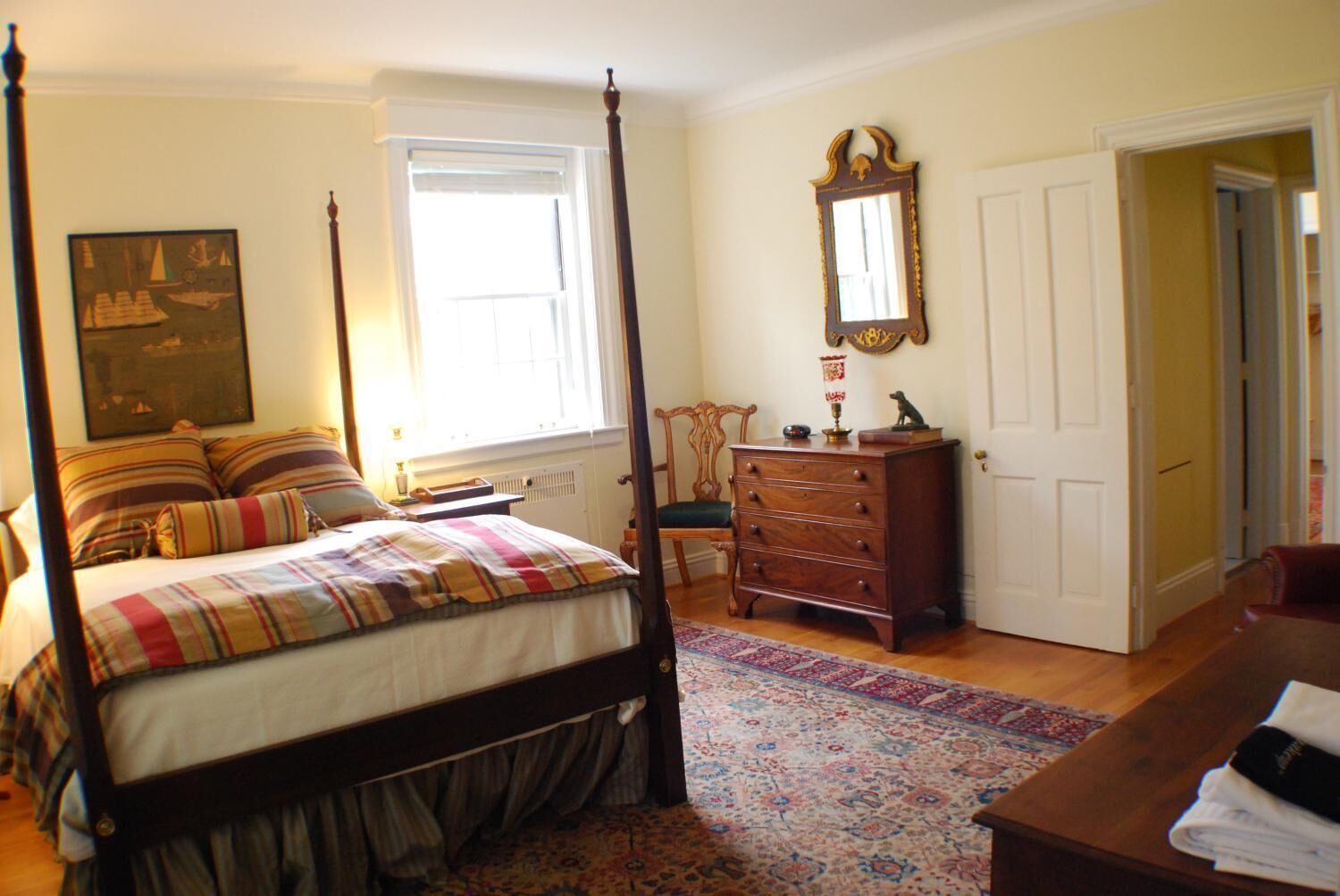 Une chambre à coucher avec un lit à baldaquin, une commode, un miroir et un tableau accroché au mur.
