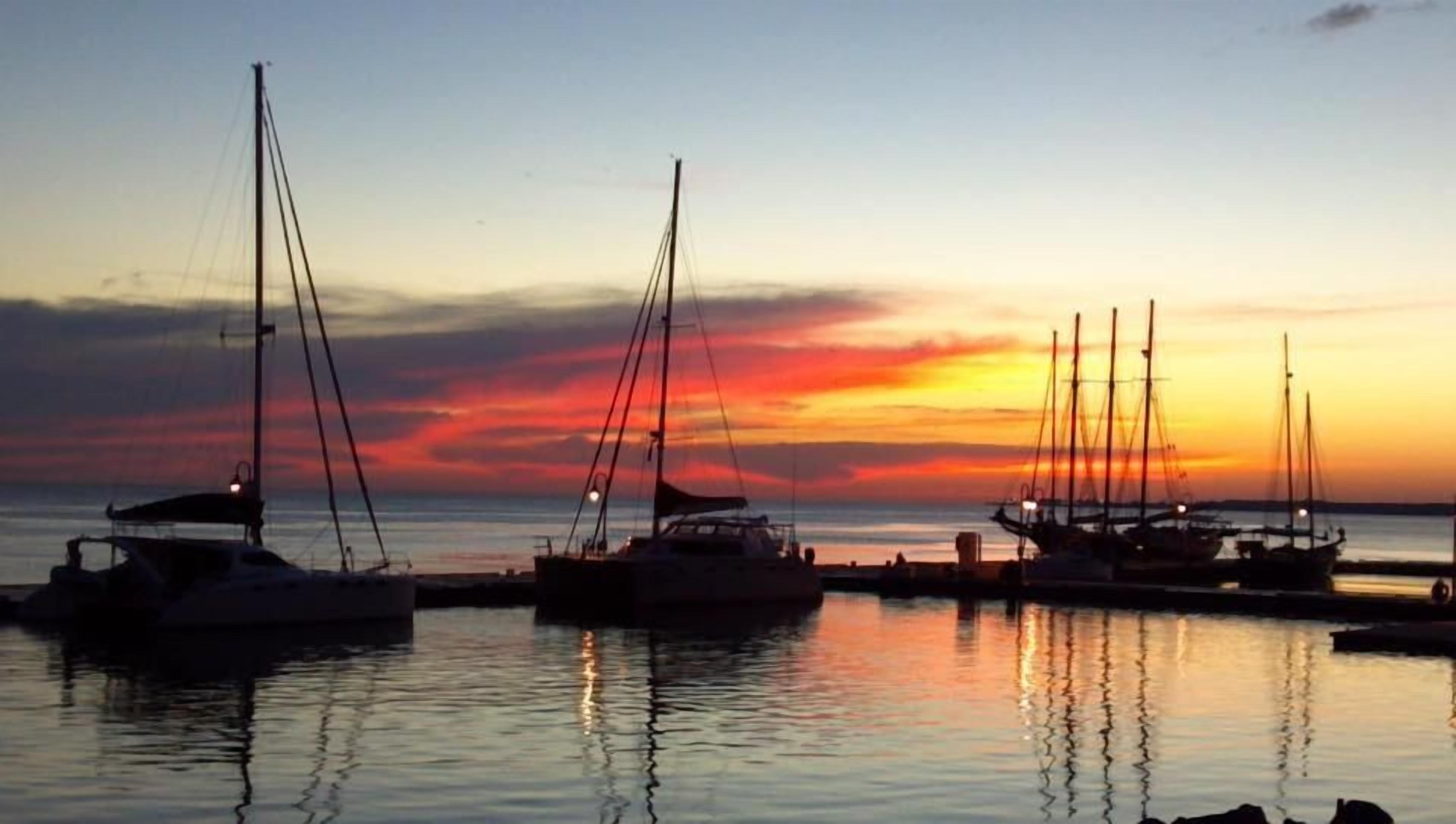A marina with several sailboats docked at sunset.