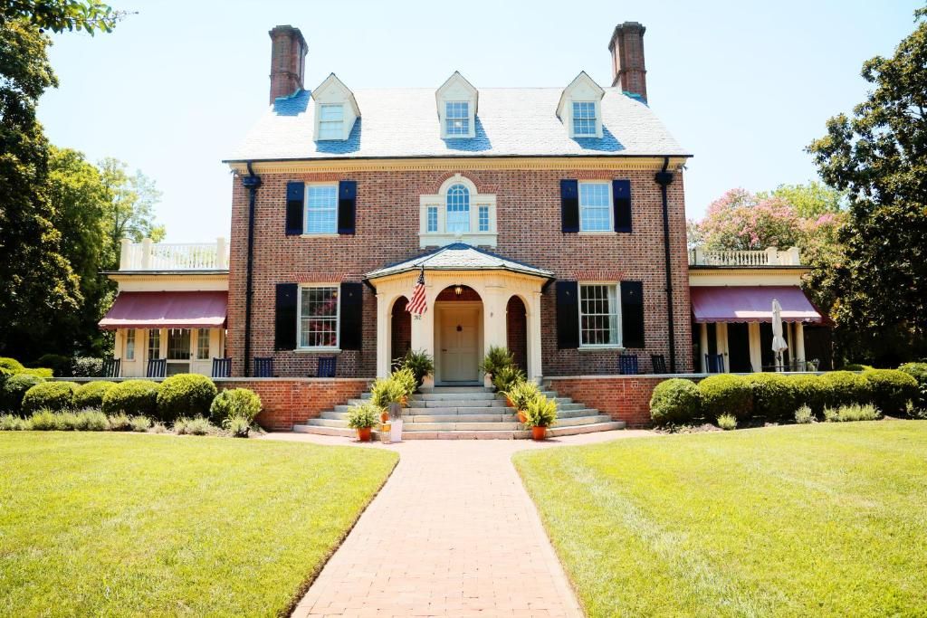 A two-story brick building with a central entrance, a flag, and a symmetrical facade.
