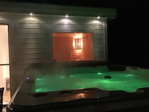 Un bain à remous doté d’une porte en bois et d’un éclairage intérieur.