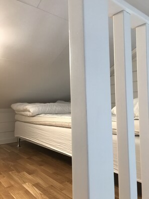 A bedroom with a bed, wooden flooring, and white walls. - Hills Loft Cottage with Sauna (Gränna)