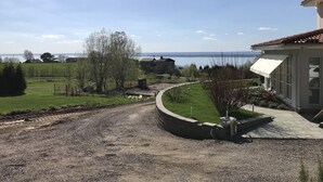 A residential property with a gravel driveway, a curved pathway, and a view of a lake. - Hills Loft Cottage with Sauna (Gränna)