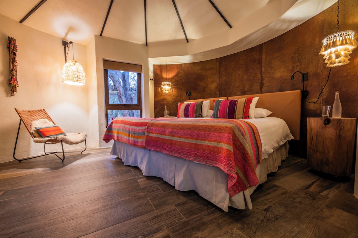 Un dormitorio moderno con una cama grande, cabecera de madera y una lámpara colgante.