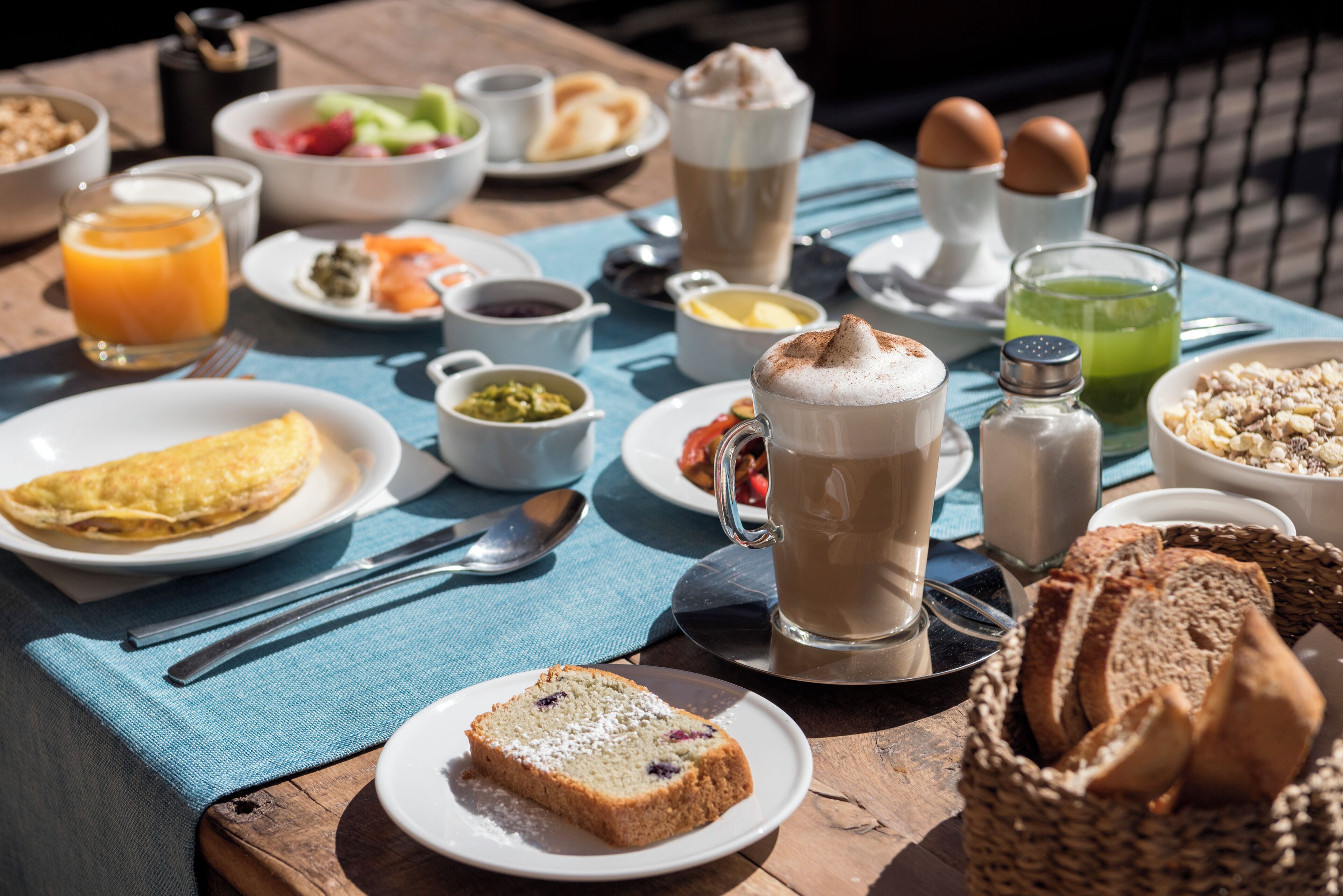 A breakfast table with various dishes, including toast, eggs, and a beverage.