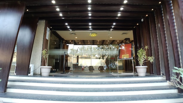 A hotel entrance with a modern design, featuring a glass facade, a staircase leading up, and potted plants. - Hotel Shiv Villas (Goharganj)