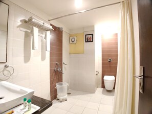 A bathroom with a sink, toilet, shower, and a small step stool. - Hotel Shiv Villas (Goharganj)