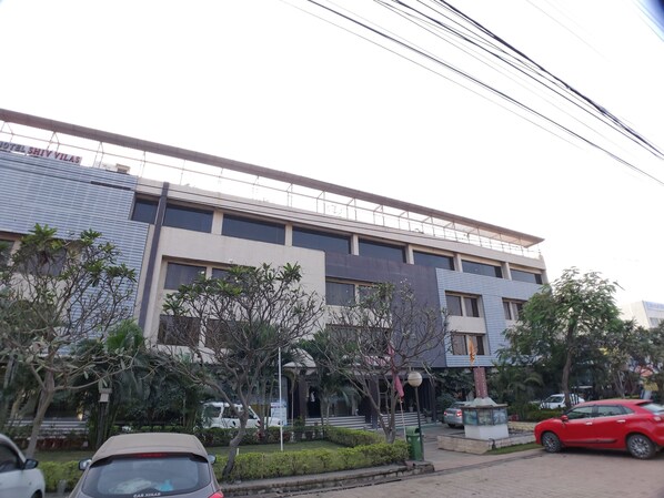 A modern hotel with multiple floors, large windows, and a well-maintained garden area. - Hotel Shiv Villas (Goharganj)