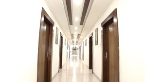 A long, well-lit hallway with doors on both sides, leading to individual rooms. - Hotel Shiv Villas (Goharganj)