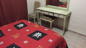 Un dormitorio con cama, mesita de noche, silla y espejo.