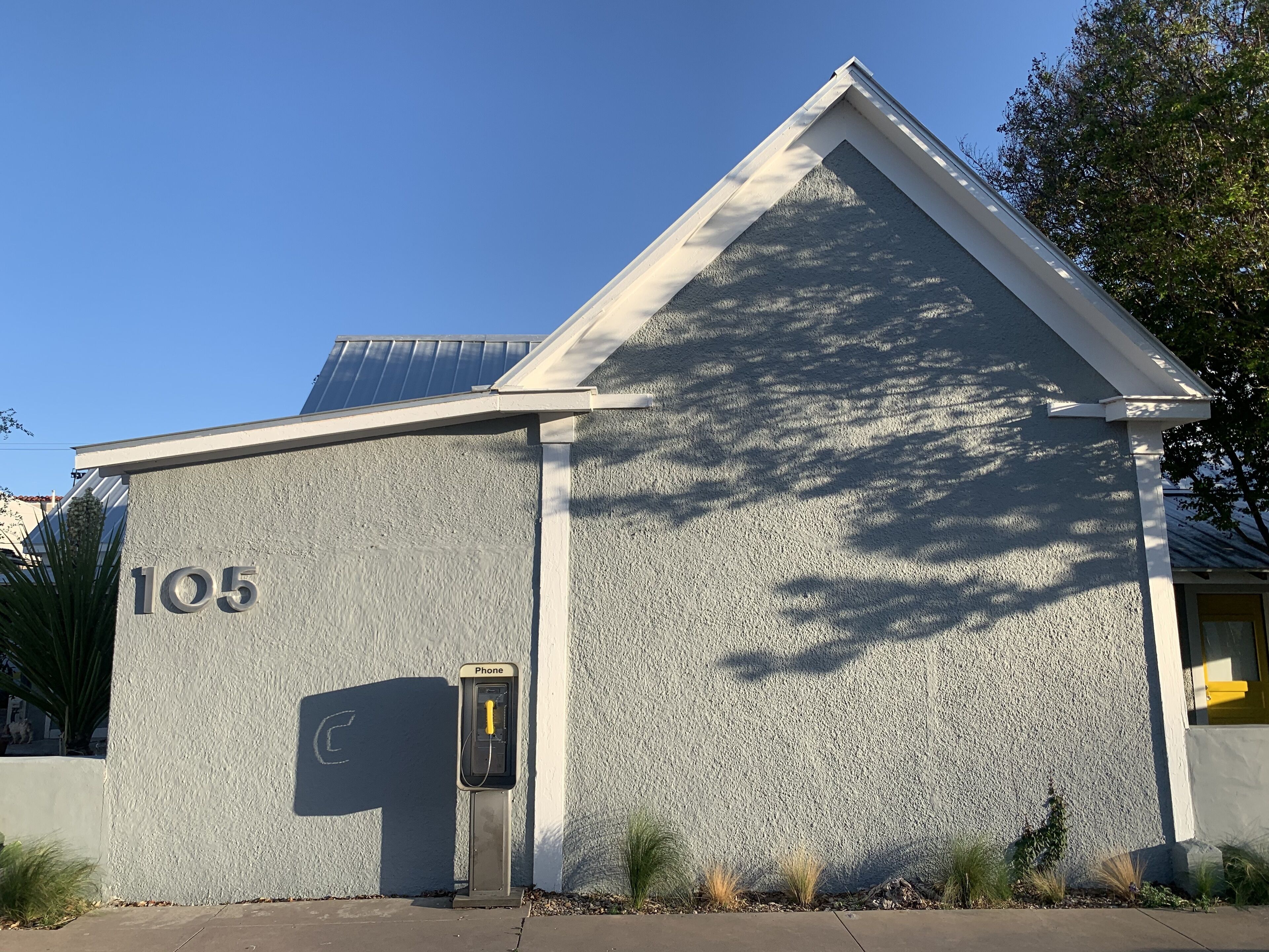 A building with a textured exterior, a number '105' on the side, and a phone charging station.