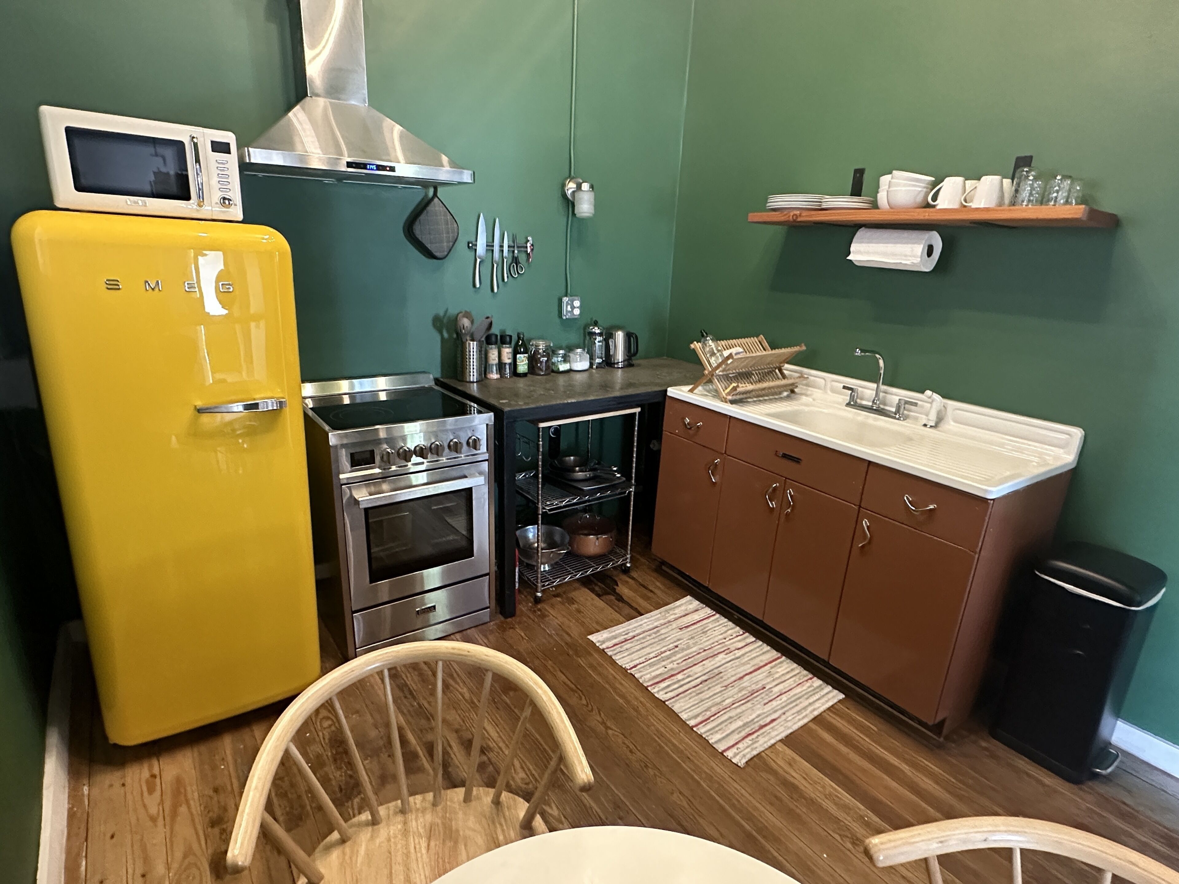 A compact kitchen with a yellow refrigerator, stainless steel stove, and a microwave.