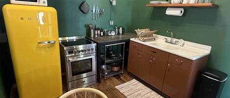 A compact kitchen with a yellow refrigerator, stainless steel stove, and a microwave.