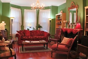A living room with a red sofa, a wooden coffee table, a red armchair, a floor lamp, and a bookshelf.
