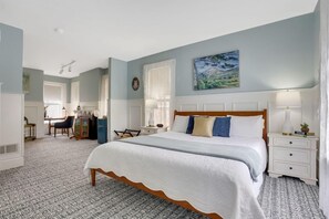 A bedroom with a large bed, a desk, and a chair.