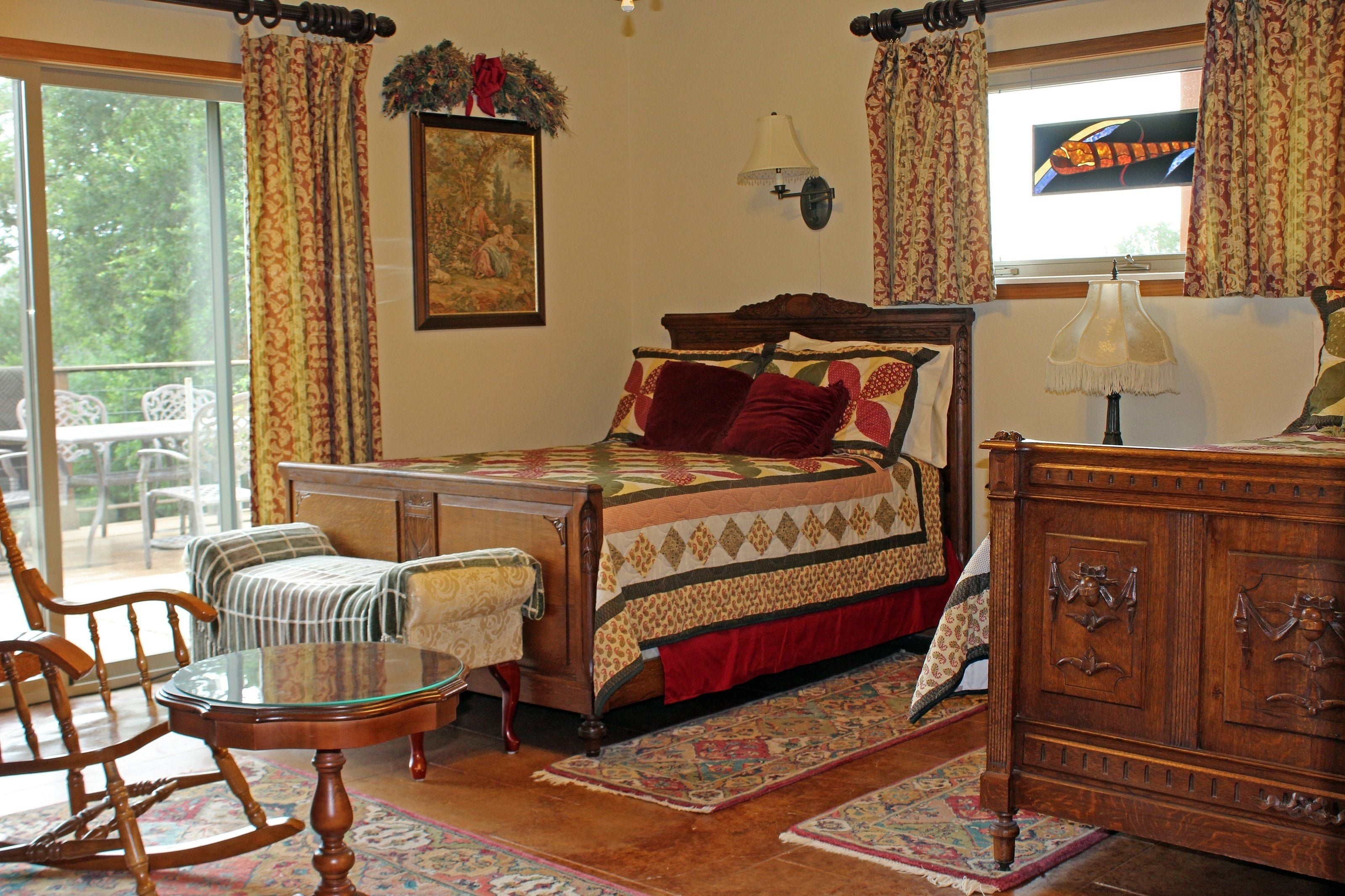 A bedroom with a bed, wooden dresser, rocking chair, and a small table.