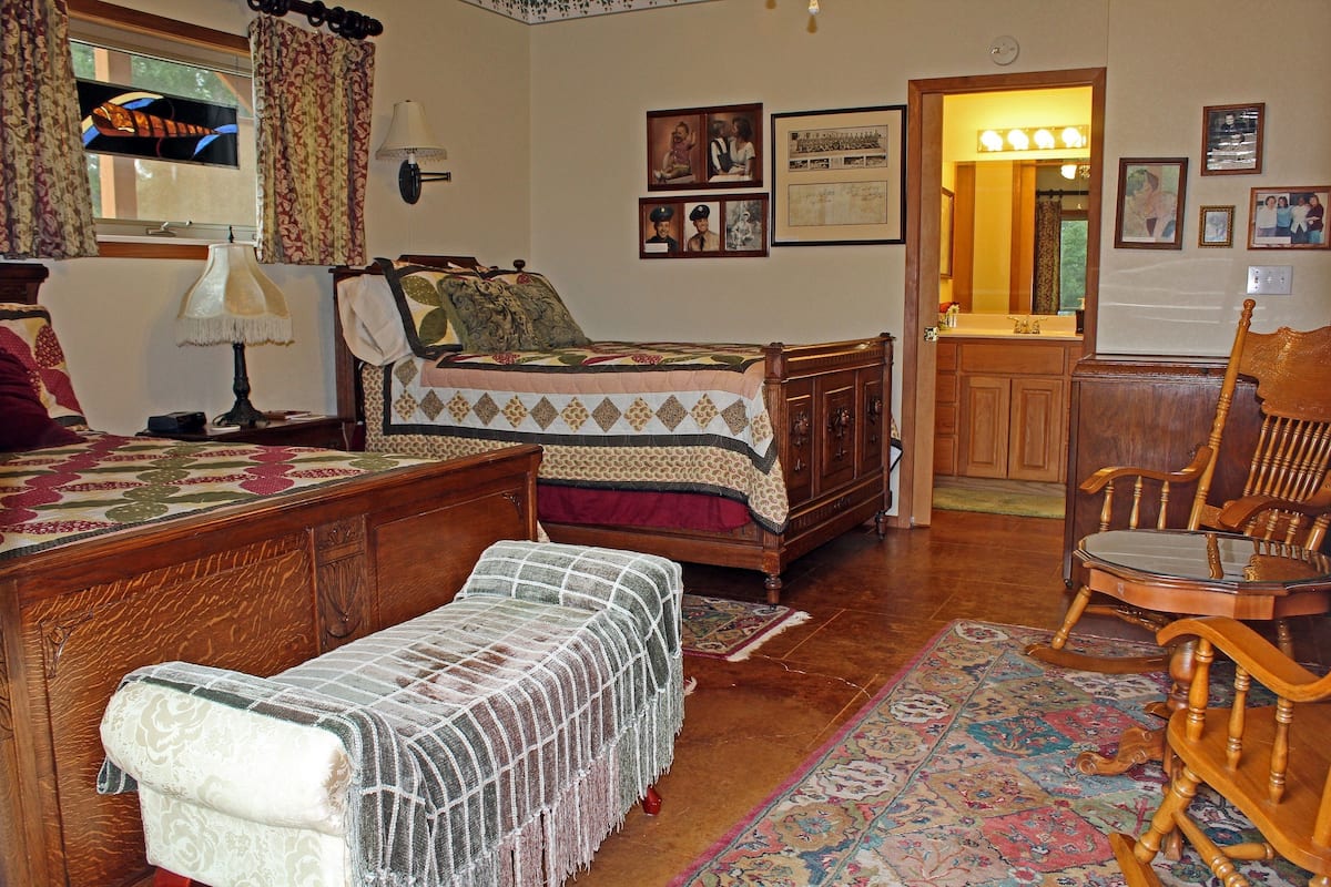 A traditional bedroom with a bed, a chair, a dresser, and a mirror.
