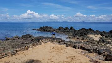 Une plage rocheuse offrant une vue dégagée sur l’océan et les montagnes lointaines.