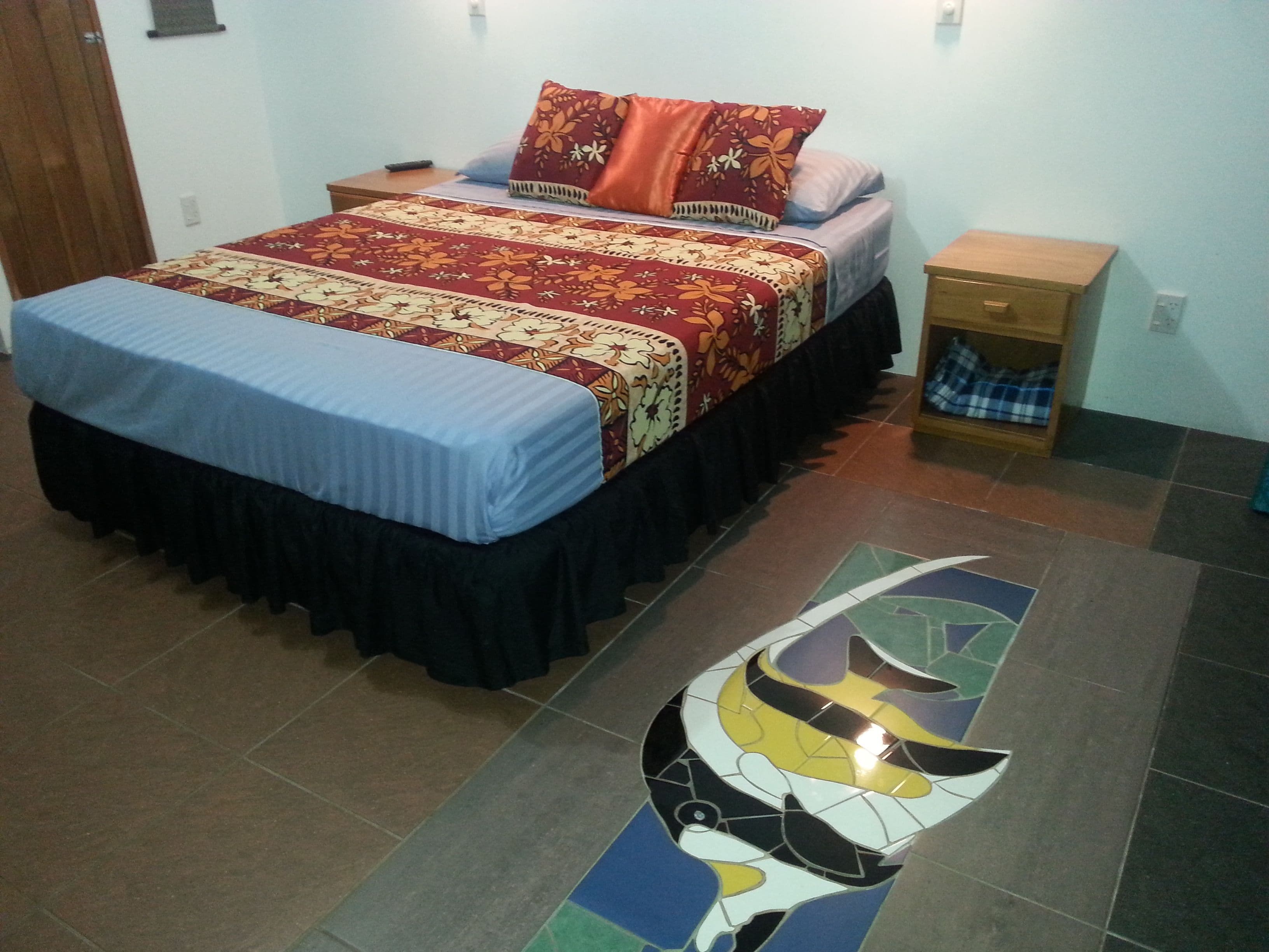 A bedroom with a bed, a nightstand, and a tiled floor.