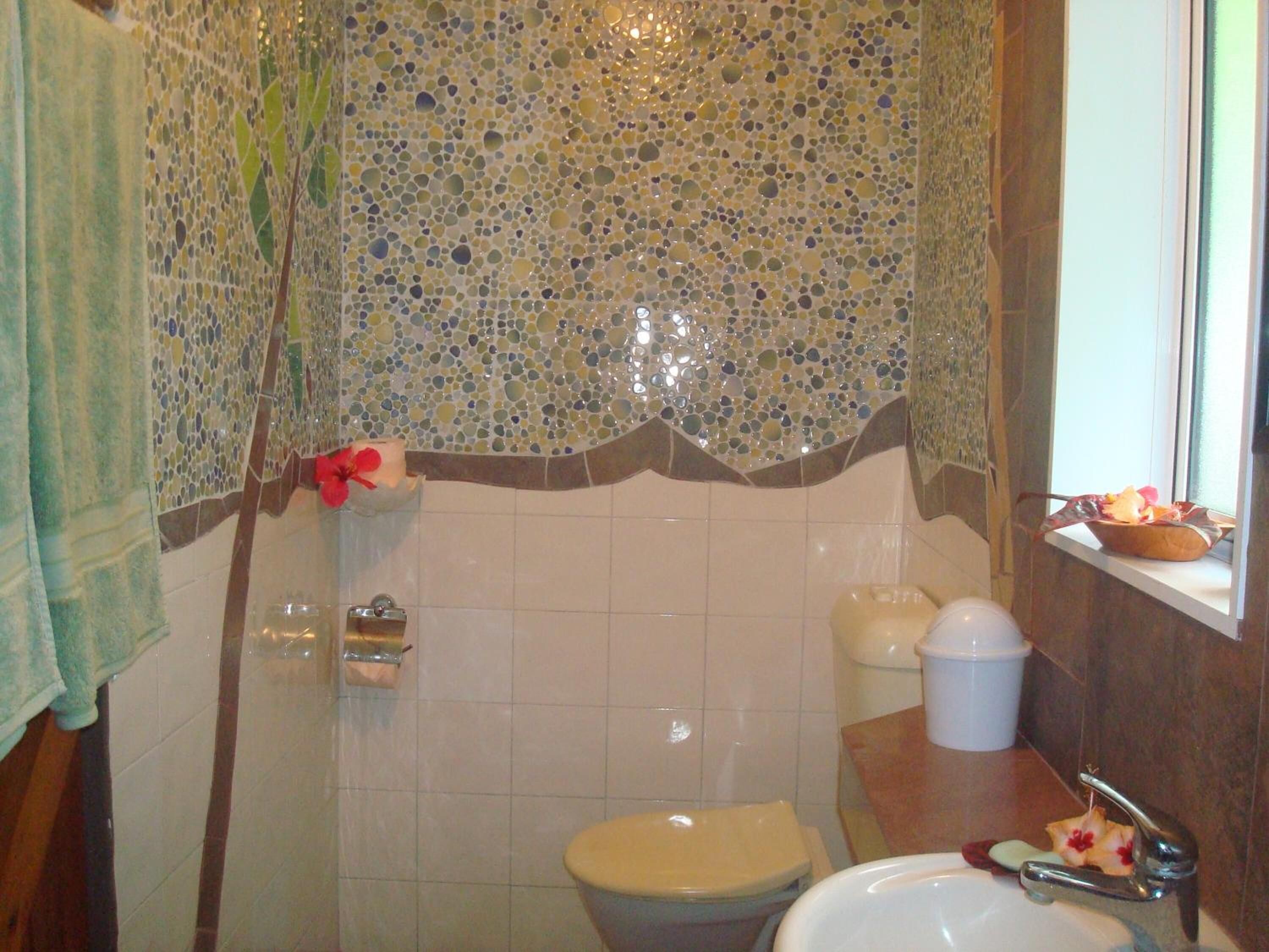Un baño con mosaicos, un inodoro, un lavabo y una ventana con vistas.