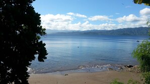 A beach with calm water, a distant mountain range, and a clear sky. - Gecko Lodge Fiji Private Hotel (Savusavu)