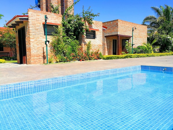 Una piscina al aire libre, sillones reclinables de piscina