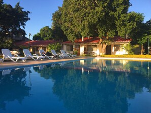 Una piscina al aire libre, sillones reclinables de piscina