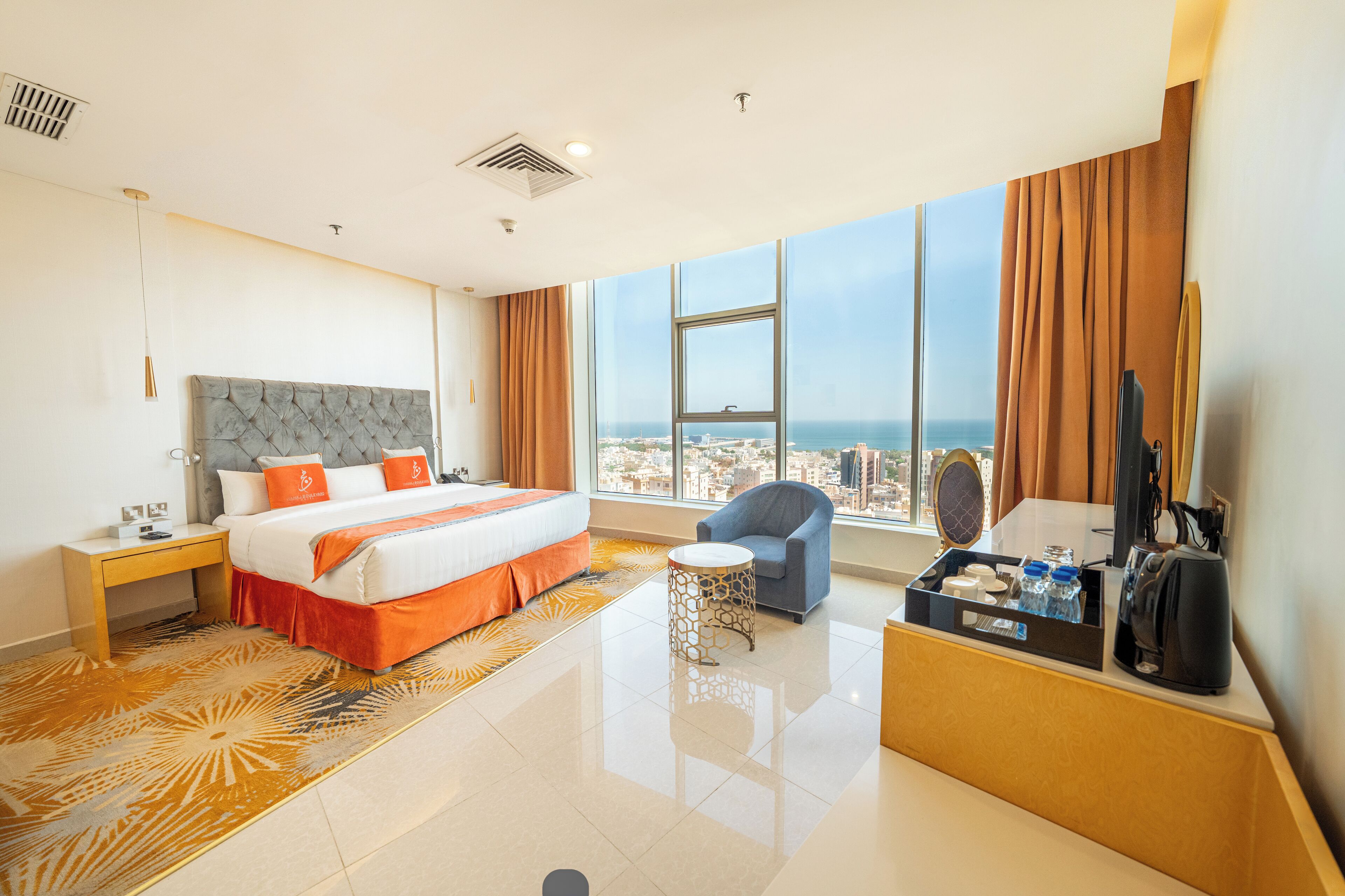 A hotel room with a large bed, a desk, a chair, and a view of the city.