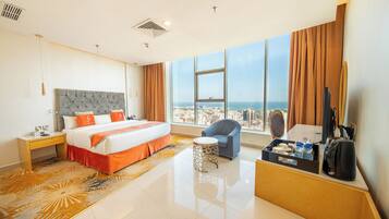 A hotel room with a large bed, a desk, a chair, and a view of the city.