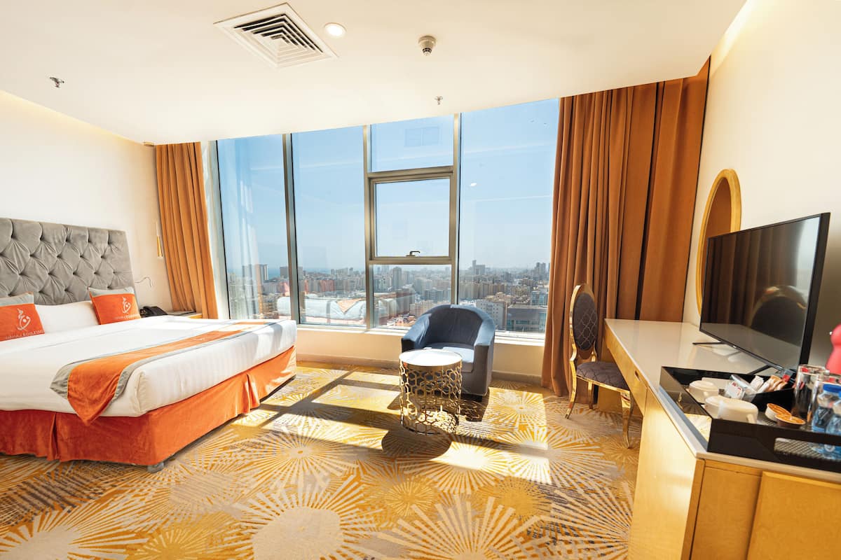 Une chambre d’hôtel avec un grand lit, une télévision, un bureau et une vue sur la ville.