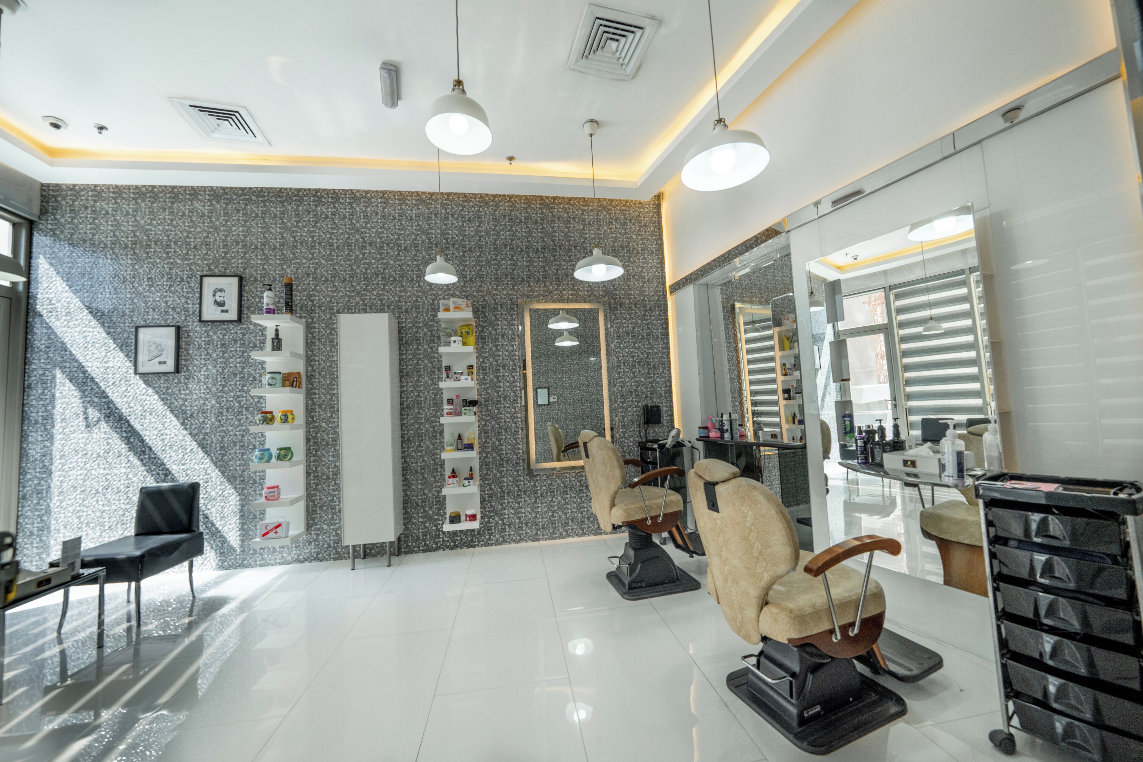 A modern salon with a large mirror, two barber chairs, and a white reception desk.