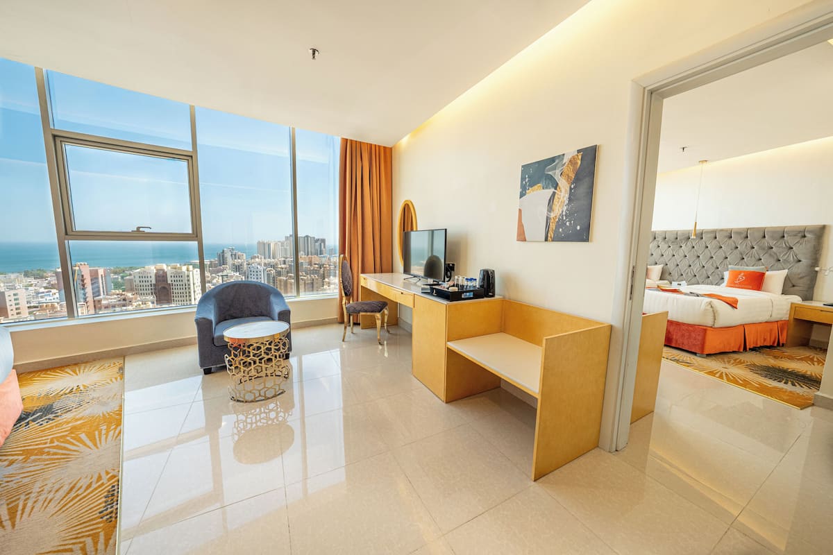 Une chambre d’hôtel moderne avec vue sur la ville, un bureau, un fauteuil confortable, un lit et une grande fenêtre.