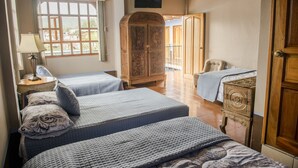Una habitación con dos camas, un armario de madera, un televisor y una ventana con cortinas.