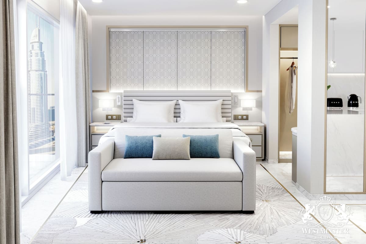 A modern hotel room with a large bed, a sofa, a bathroom, and a view of a cityscape.