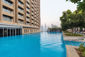 A swimming pool with a city skyline in the background, surrounded by a high-rise building and a tree-lined area. - Westminster Dubai Mall (Dubai)