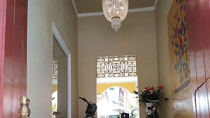 Een trap leidt naar een balkon met een decoratieve plafondlamp, een bord aan de muur en twee fietsen op de treden.