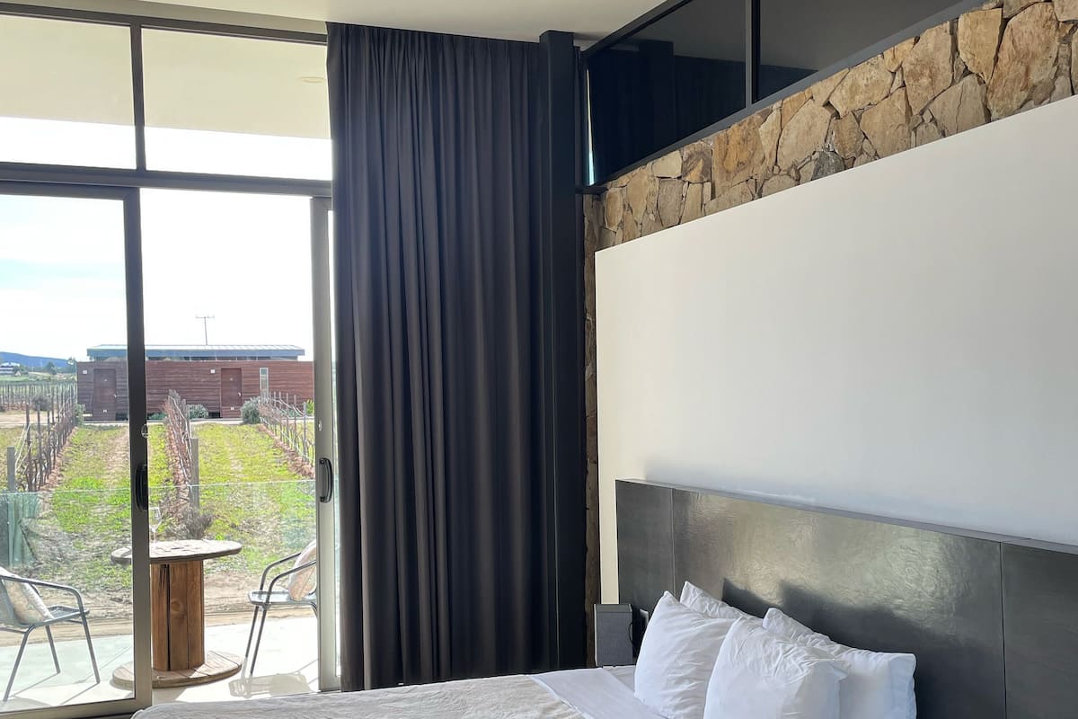 Une chambre d’hôtel moderne avec un grand lit, un mur décoratif en pierre et une vue sur l’extérieur.