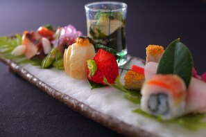 A variety of sushi pieces arranged on a rectangular plate with a dark background.