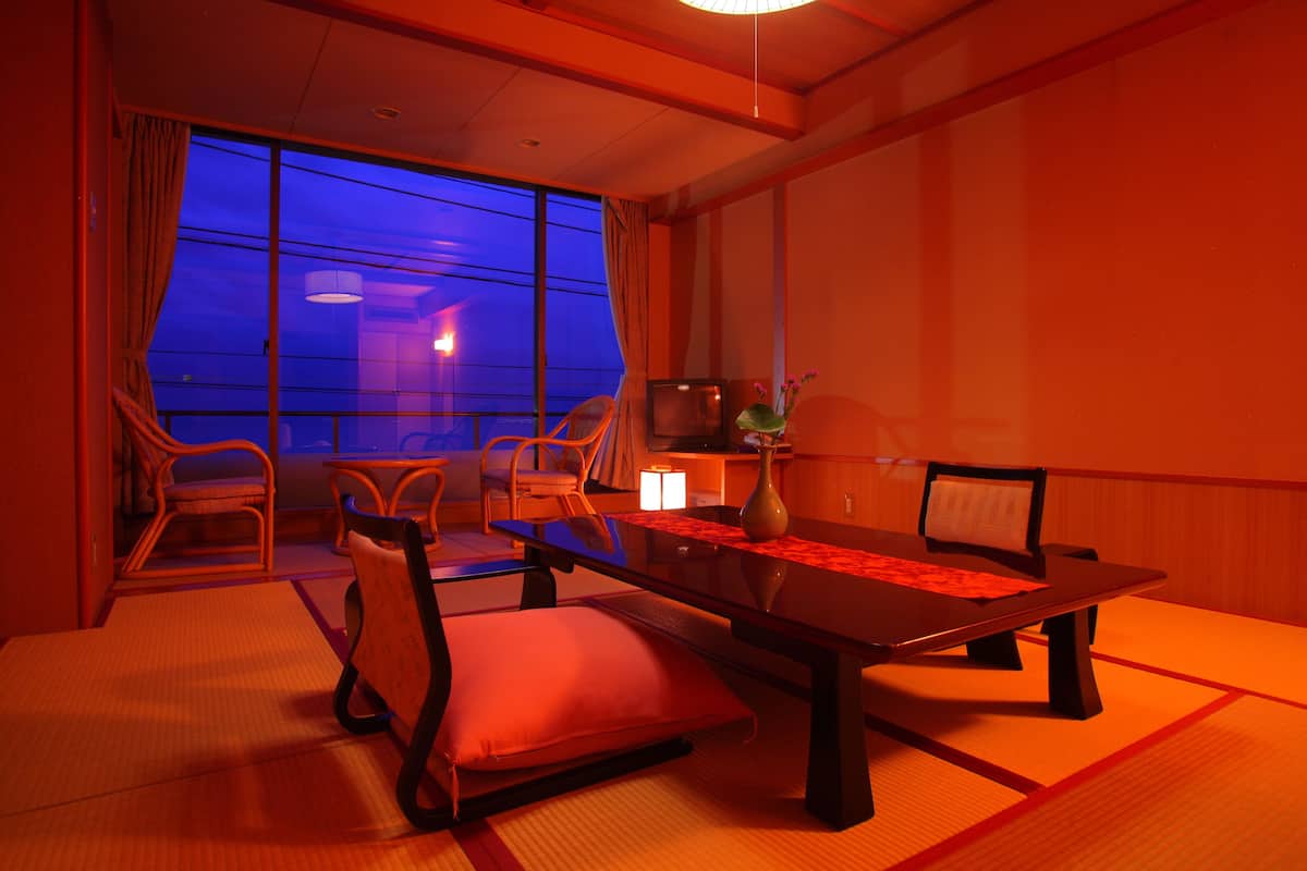 A traditional Japanese-style room with tatami flooring, a low table, and wooden chairs.